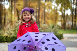 Little girl standing behind a purple umbrella