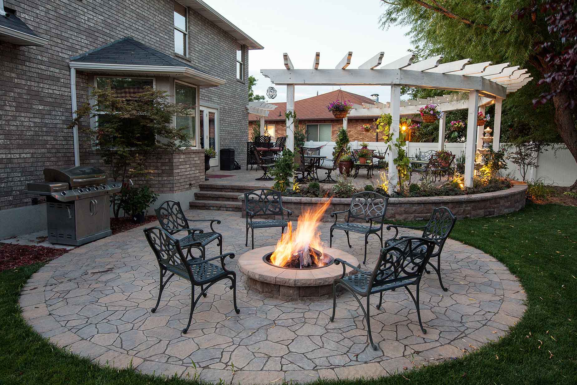burning fire surrounded by outdoor seating with pergola in background