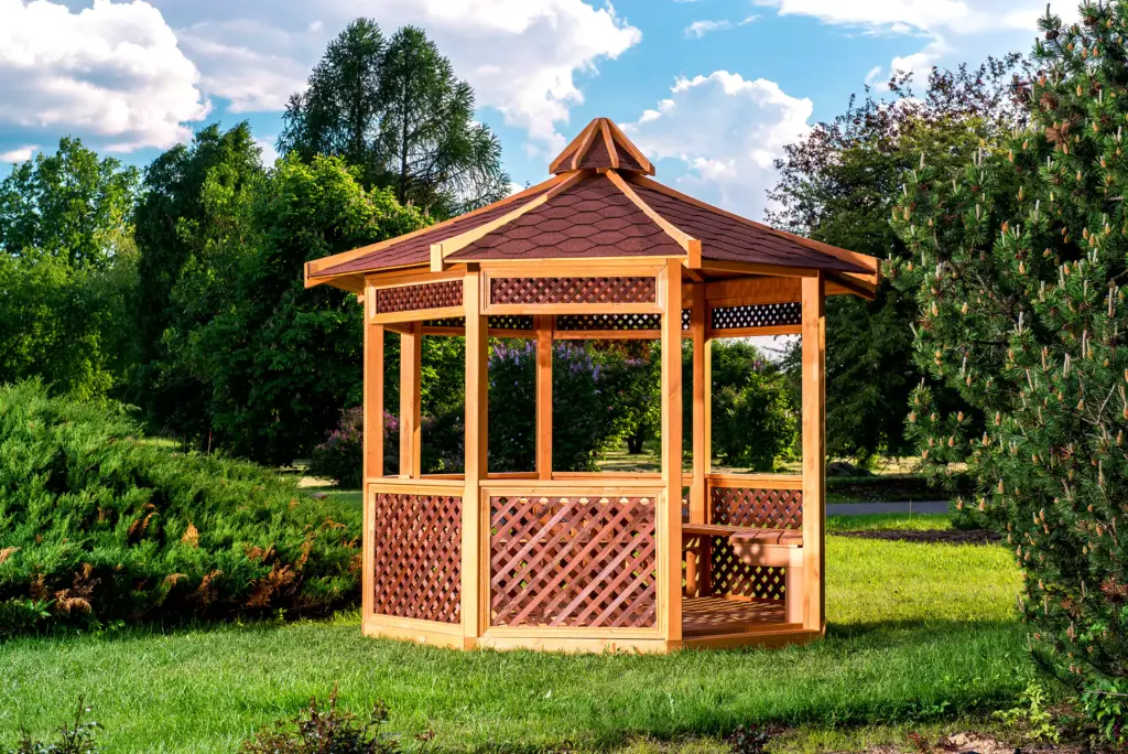 A wooden gazebo in a backyard lawn