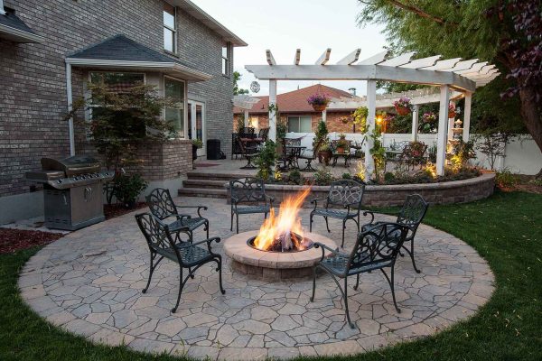 burning fire surrounded by outdoor seating with pergola in background